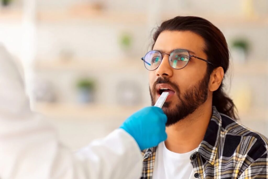Healthcare worker in protective gear performing a throat swab test on a man