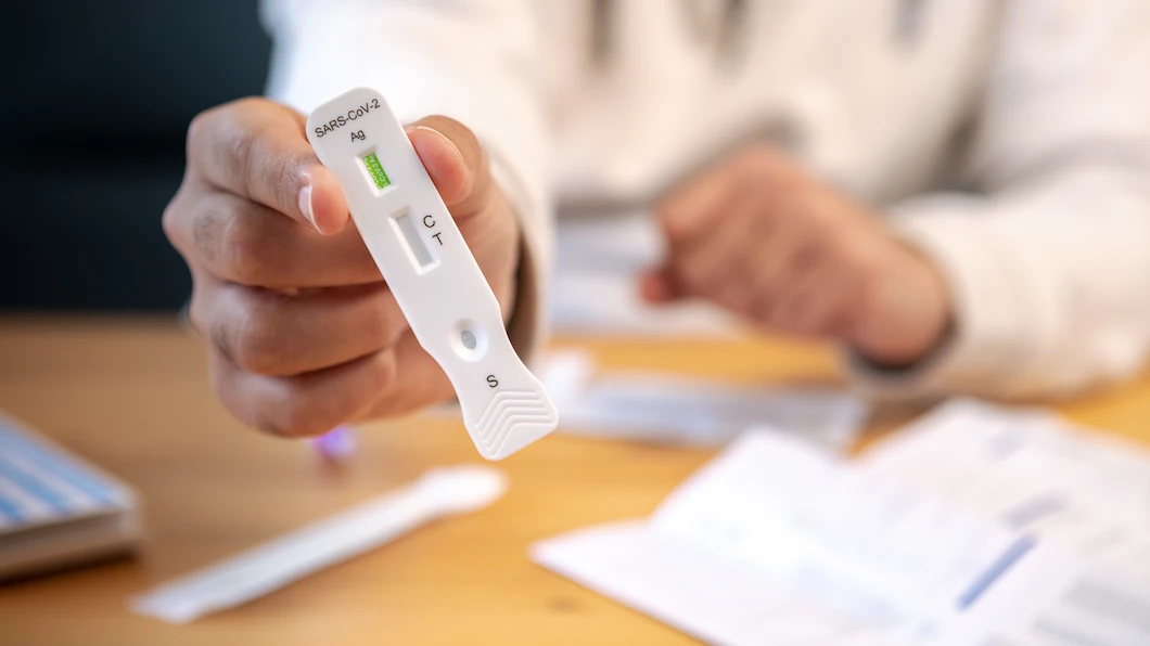 Hand holding a SARS-CoV-2 antigen rapid test cassette with C and T result lines