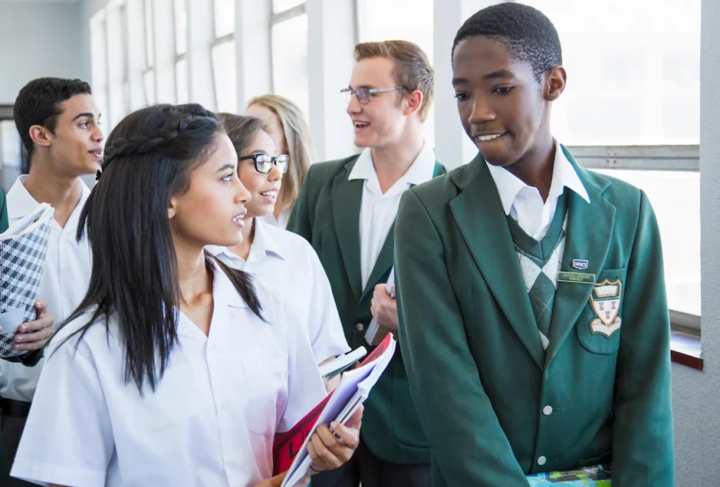 Group of school pupils in uniform carrying books, walking together in a corridor
